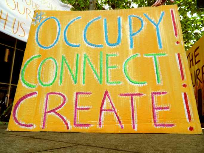 Large Cardboard protes sign reading "OCCUPY! CONNECT! CREATE!"