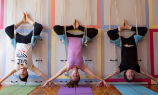 Three women hanging upside down in the Samamkaya Yoga Collective studio.