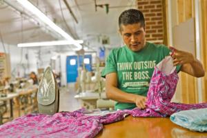 Walter Vicente, a worker-owner at Opportunity Threads, works on a custom dress. Photo by Dana Dillehunt.