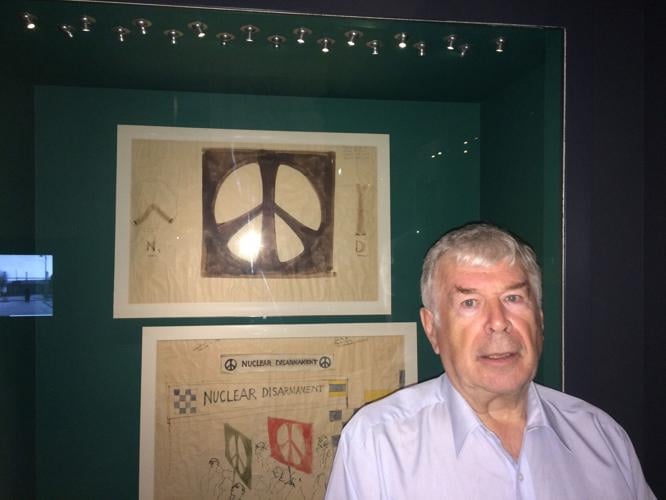 David Thompson standing in front of the original sketches of the Peace Sign by Gerald Holcomb.