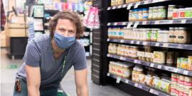 co-op employee placing social distancing graphic on the floor of a grocery aisle.