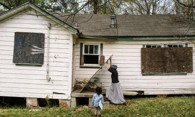 Nia Umoja pushes a piece of plywood against a doorway on an abandoned house acquired by the Cooperative Community of West Jackson, which plans to restore the building to function as a center for folk art. Photo by William Widmer/ReduxPictures